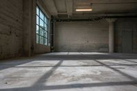 the sun is shining through the large windows of an empty room in a factory building