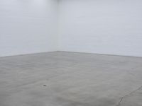 a large white brick wall in a empty room, with a skateboard on the floor