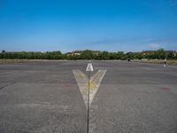 the arrow is in between two lines at an airport runway that are empty and one yellow