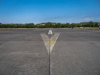 the arrow is in between two lines at an airport runway that are empty and one yellow