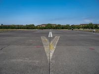 the arrow is in between two lines at an airport runway that are empty and one yellow