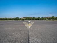 the arrow is in between two lines at an airport runway that are empty and one yellow