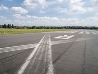 an empty runway is seen from the ground in daylight light with clouds in the sky