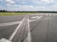 an empty runway is seen from the ground in daylight light with clouds in the sky