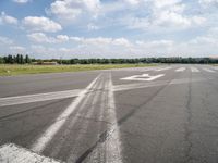 an empty runway is seen from the ground in daylight light with clouds in the sky