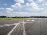 an empty runway is seen from the ground in daylight light with clouds in the sky