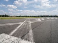 an empty runway is seen from the ground in daylight light with clouds in the sky