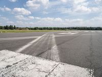 an empty runway is seen from the ground in daylight light with clouds in the sky