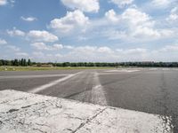 an empty runway is seen from the ground in daylight light with clouds in the sky