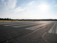 an empty runway with trees in the background and two lines drawn out on the pavement