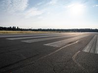 an empty runway with trees in the background and two lines drawn out on the pavement