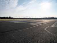 an empty runway with trees in the background and two lines drawn out on the pavement