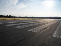 an empty runway with trees in the background and two lines drawn out on the pavement