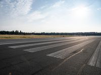 an empty runway with trees in the background and two lines drawn out on the pavement