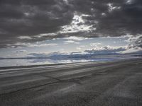 an empty runway and some clouds and a blue sky with some trees on it next to a beach