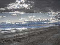 an empty runway and some clouds and a blue sky with some trees on it next to a beach