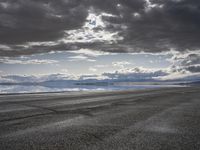 an empty runway and some clouds and a blue sky with some trees on it next to a beach