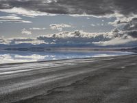 an empty runway and some clouds and a blue sky with some trees on it next to a beach