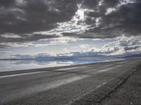 an empty runway and some clouds and a blue sky with some trees on it next to a beach