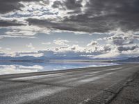 an empty runway and some clouds and a blue sky with some trees on it next to a beach