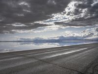 an empty runway and some clouds and a blue sky with some trees on it next to a beach