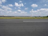 a airplane sitting on an empty runway in front of a building with a clock tower