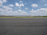 a airplane sitting on an empty runway in front of a building with a clock tower