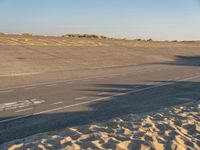 a large empty runway that is going towards the desert and the field to the side