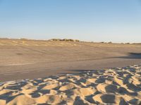 a large empty runway that is going towards the desert and the field to the side