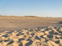 a large empty runway that is going towards the desert and the field to the side