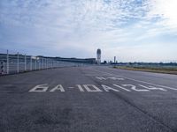 an empty runway with the word'no parking'written on it and the airport building in the background