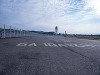 an empty runway with the word'no parking'written on it and the airport building in the background