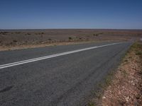 an empty rural highway with blue skies in the distance and no cars on it,