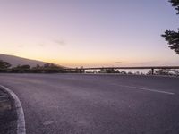 a motorcycle sits parked near an empty highway at sunset or night on a mountain trail