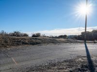 a view of a empty rural street in an open field, with a single red fire hydrant nearby