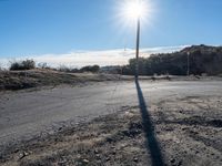 a view of a empty rural street in an open field, with a single red fire hydrant nearby