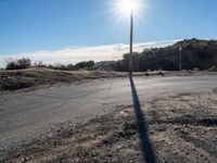 a view of a empty rural street in an open field, with a single red fire hydrant nearby