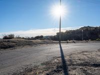 a view of a empty rural street in an open field, with a single red fire hydrant nearby