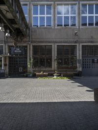 an empty sidewalk with benches in front of the buildings near by it and some windows