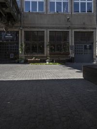 an empty sidewalk with benches in front of the buildings near by it and some windows