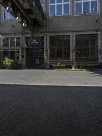 an empty sidewalk with benches in front of the buildings near by it and some windows