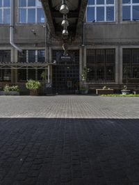 an empty sidewalk with benches in front of the buildings near by it and some windows