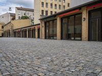 this empty sidewalk is full of old fashioned items and brick buildings with glass doors on each side