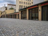 this empty sidewalk is full of old fashioned items and brick buildings with glass doors on each side