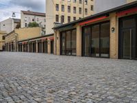 this empty sidewalk is full of old fashioned items and brick buildings with glass doors on each side