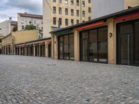 this empty sidewalk is full of old fashioned items and brick buildings with glass doors on each side