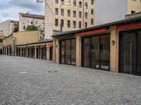 this empty sidewalk is full of old fashioned items and brick buildings with glass doors on each side