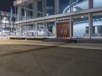 an empty sidewalk in front of a glassed building with two lights in the corner