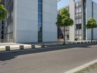 an empty sidewalk next to a tall building on a city street with no cars and a man sitting in a chair