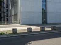 an empty sidewalk next to a tall building on a city street with no cars and a man sitting in a chair